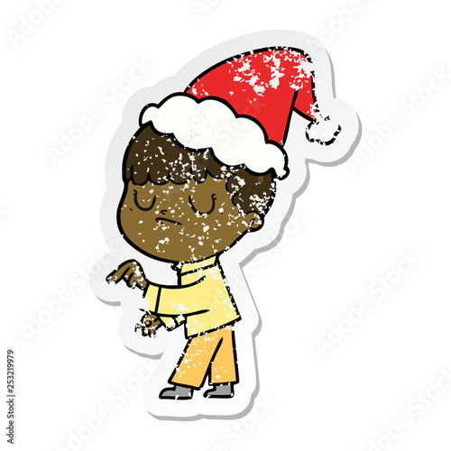 distressed sticker cartoon of a grumpy boy wearing santa hat