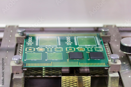 close up green electronic printed circuit board (pcb) for computer or equipment setup on jig at work table photo