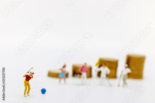 Miniature people: Golfers hit golf balls up to the top coins,  Finance, investment and growth in business concept. © Rattana.R