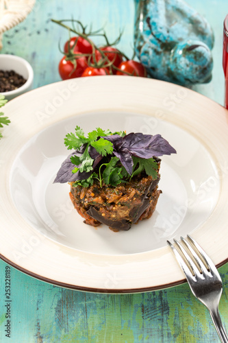 Baked eggplant with basil on top on blue wooden table