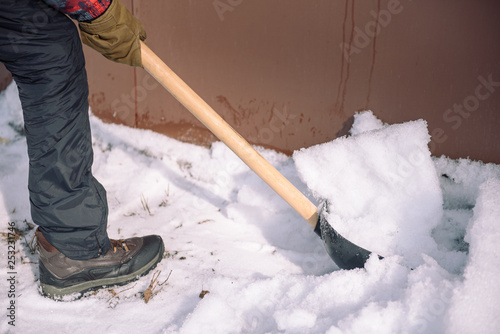 Clean the snow with a shovel. The man shovels snow shovels. Snow shovel in hand. Cleaning the area in the winter.