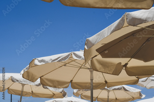 View of the blue sky at a beach on a sunny day with parasols for shade. 