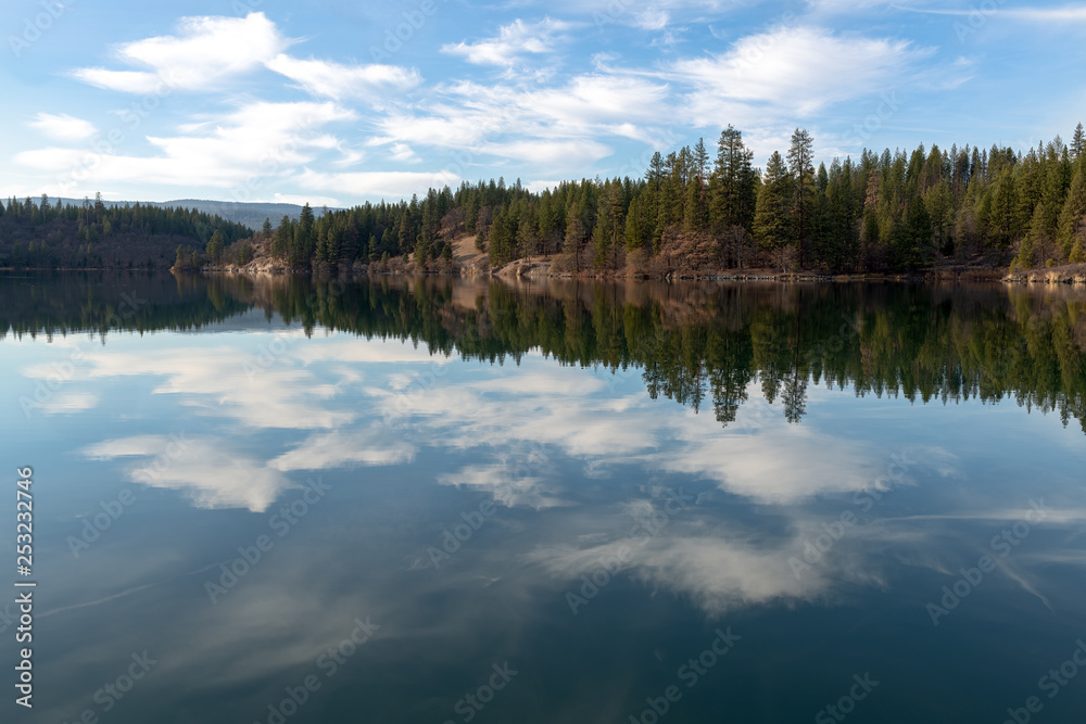 Trees and clouds reflected in Lake Britton in McArthur Burney Falls Memorial State Park, California, USA