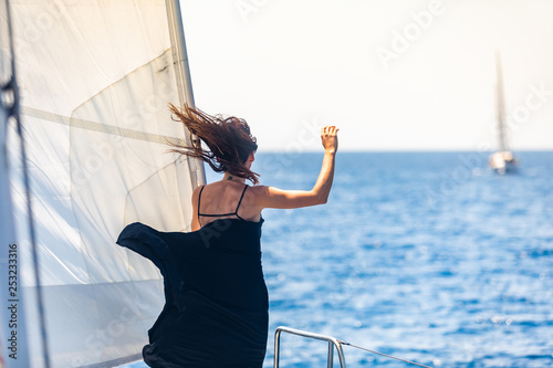 Girl in a black dress on the nose of the yacht photo