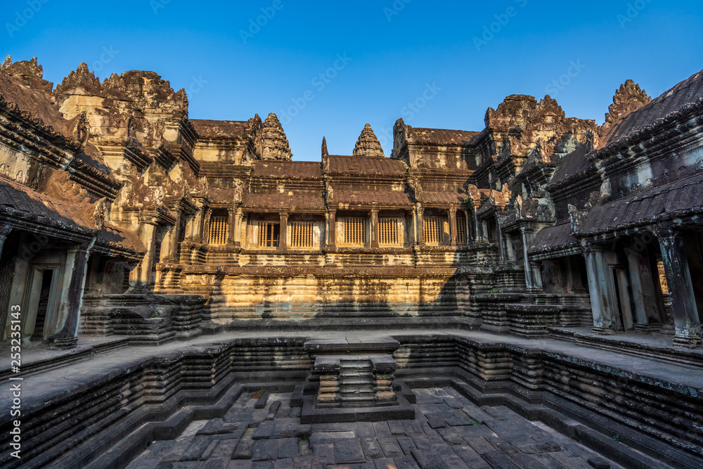 Open paved courts and covered galleries in Angkor Wat temple in golden sunset light