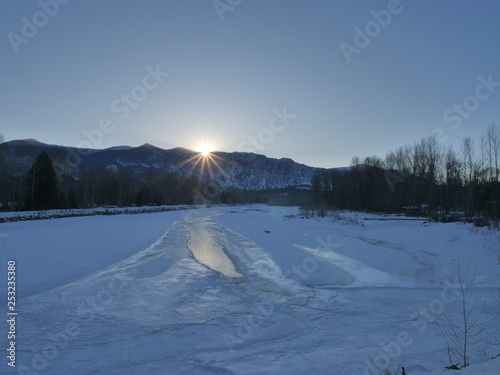 cold winter sunrise scene along a frozen river © Redfisherstudio