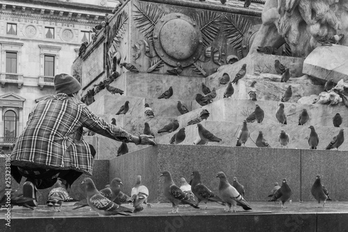 Boy feed pigeons in Milan a black and white photo