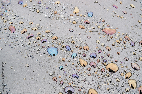 rows of water droplets on the dark surface of bitumen, a mixture of water and petroleum macro