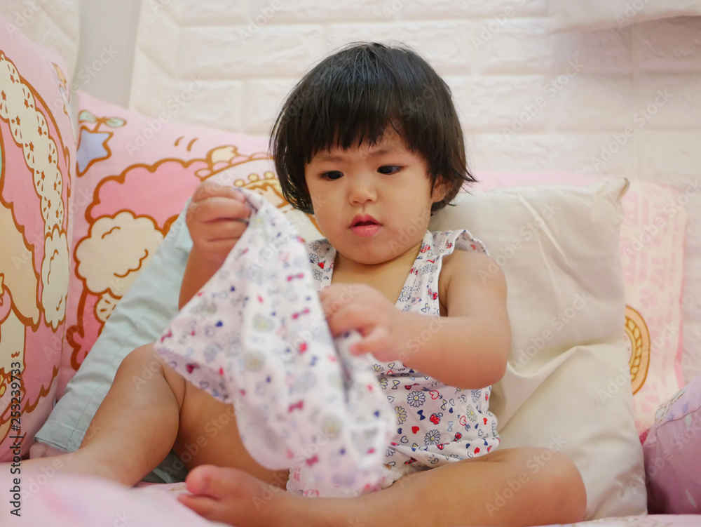 Little Asian baby girl, 23 months old, learning to put on short pants by herself - child development by allowing them to do things by themselves Little Asian baby girl, 23 months old, learning to put on short pants by herself - child development by allowing them to do things by themselves