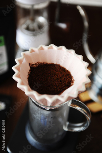 Ground coffee in pink ceramic origami dripper with paper filter close up. Alternative coffee manual hand brewing photo