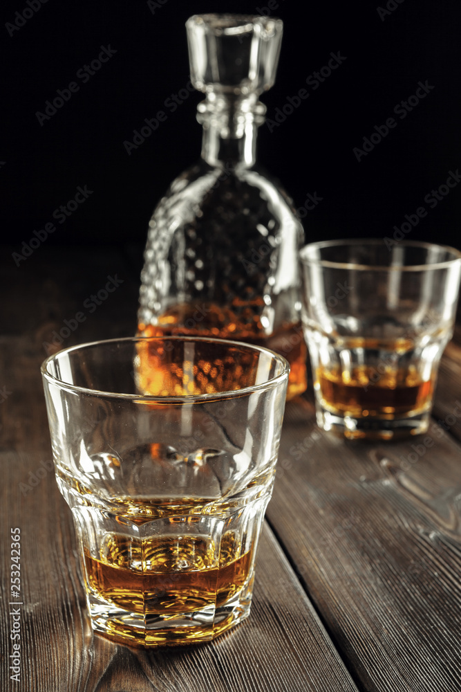 Whiskey glass and bottle on the old wooden table Whiskey glass and bottle on the old wooden table