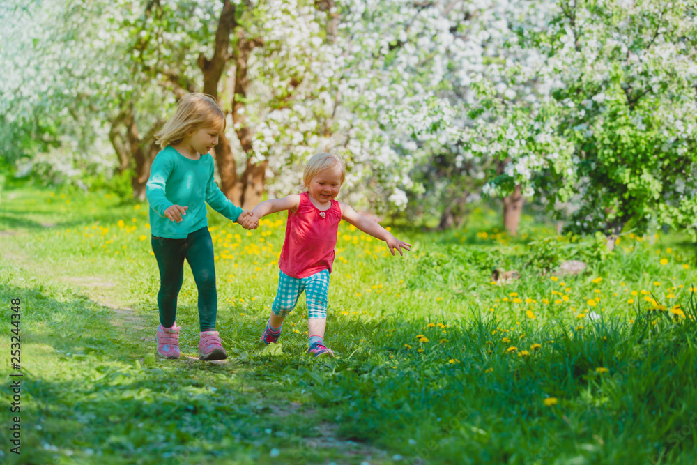 happy girls play run in spring nature, apple blossom