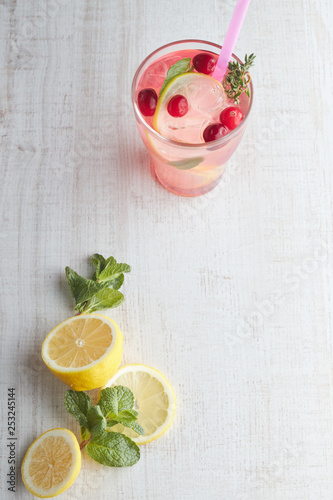 Refreshing summer drink with berry and lemon on a light wooden table. The concept of summer drinks with ice. glass with summer cocktail with straw.