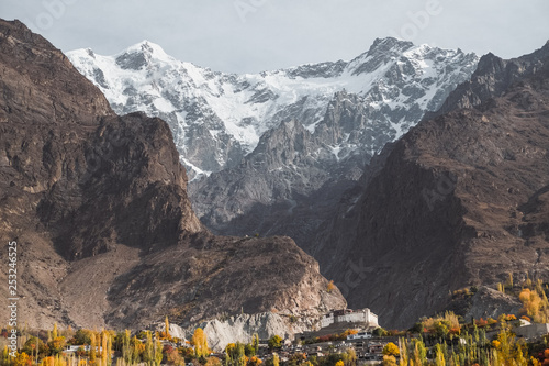 Landscape view of snow capped Ultar Sar mountain in Karakoram range with ancient Baltit fort and foliage in autumn in Karimabad. Hunza valley, Gilgit Baltistan, Pakistan. photo