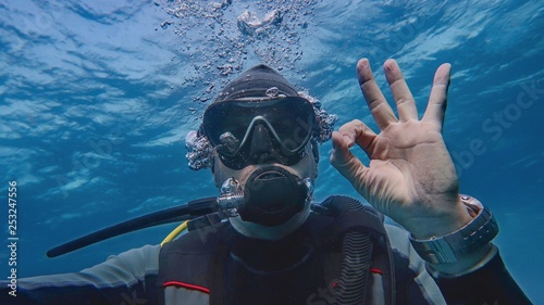 Obraz na plátně Man scuba diver underwater showing signal OK