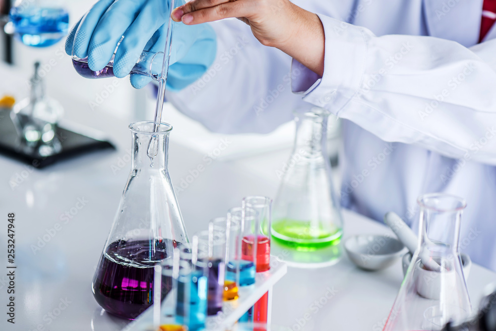 Fototapeta premium Scientist holding sampling oil or chemical liquid in flask with lab glassware in laboratory background, science or medical research and development concept 