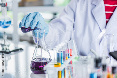 Scientist holding sampling oil or chemical liquid in flask with lab glassware in laboratory background, science or medical research and development concept  