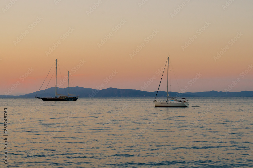 Silhouettes of yachts on the background of orange sunset 