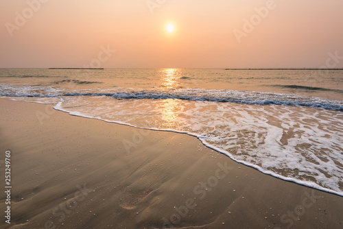 reflection of sunrise above the sea wave on the beach