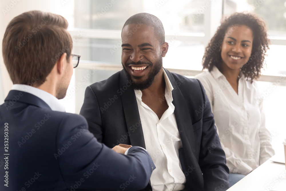 Multi-ethnic colleagues shaking hands greeting each other during briefing Multi-ethnic colleagues shaking hands greeting each other during briefing