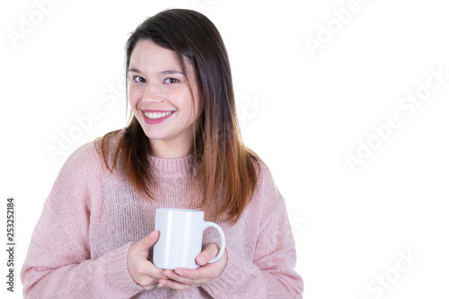 Girl in a warm pink sweater is holding white mug in hands