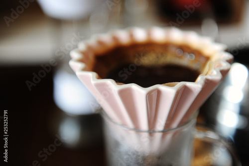 Alternative manual hand coffee brewing in pink ceramic origami dripper with paper filter. Close up photo