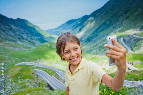 Cute boy making a selfie photo of Transfagarasan mountain road. Romania. photo
