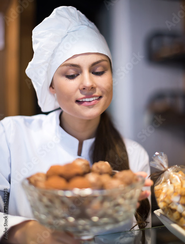 beautiful shopgirl working in bakery with bread and different pastry photo