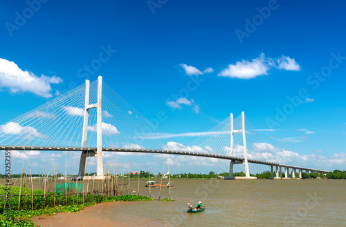 Dong Thap, Vietnam - January 17th, 2019: Fishermen are fishing in a small boat in the middle of the river, a cable-stayed bridge that represents the economic development in Dong Thap, Vietnam.