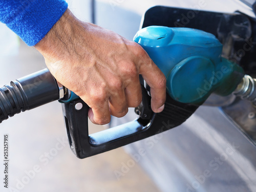 Closeup hand man pumping gasoline fuel in car at gas station.
