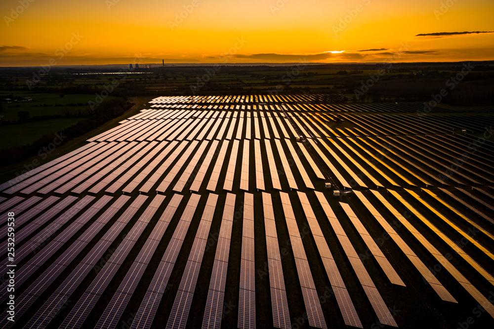 Aerial looking over a modern solar farm at sunrise in the English countryside panoramic