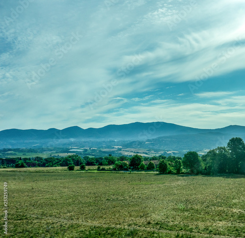 Italy, Rome to Florence train, a large green field with trees in the background © SkandaRamana