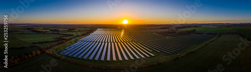 Aerial looking over a modern solar farm at sunrise in the English countryside panoramic