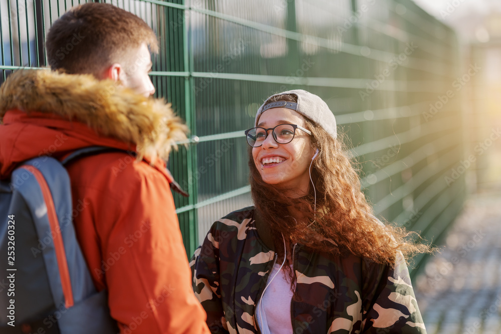 Beautiful smiling mixed race teenage girl meeting her boyfriend outdoors.