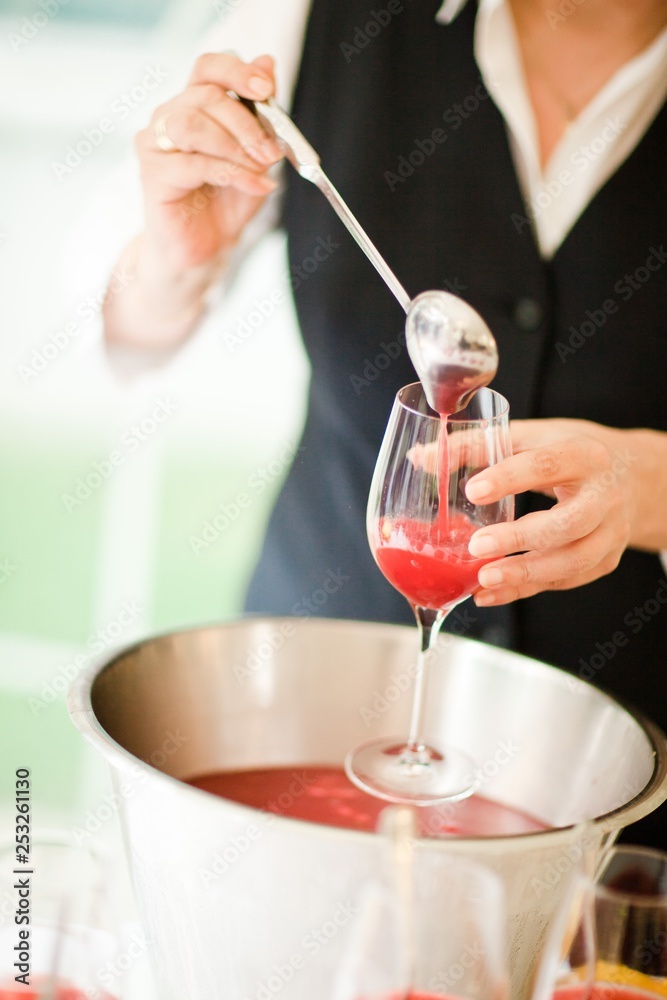 Barman pouring red cocktail- cup on the stem.