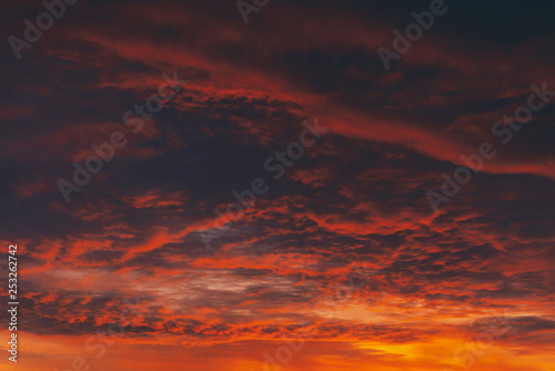 Fiery red blood vampire dawn. Amazing warm dramatic fire cloudy sky. Vivid orange sunlight. Atmospheric background of sunrise in overcast weather. Hard cloudiness. Storm clouds warning. Copy space.