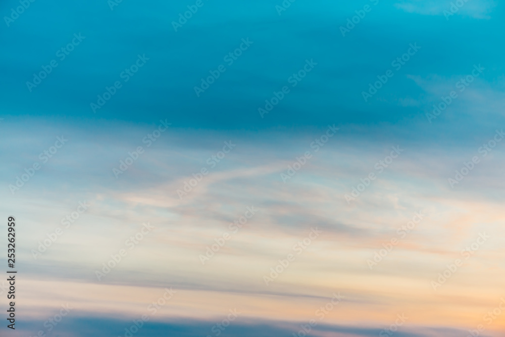 Sunset sky with orange yellow light clouds. Colorful smooth blue sky gradient. Natural background of sunrise. Amazing heaven at morning. Slightly cloudy evening atmosphere. Wonderful weather on dawn.