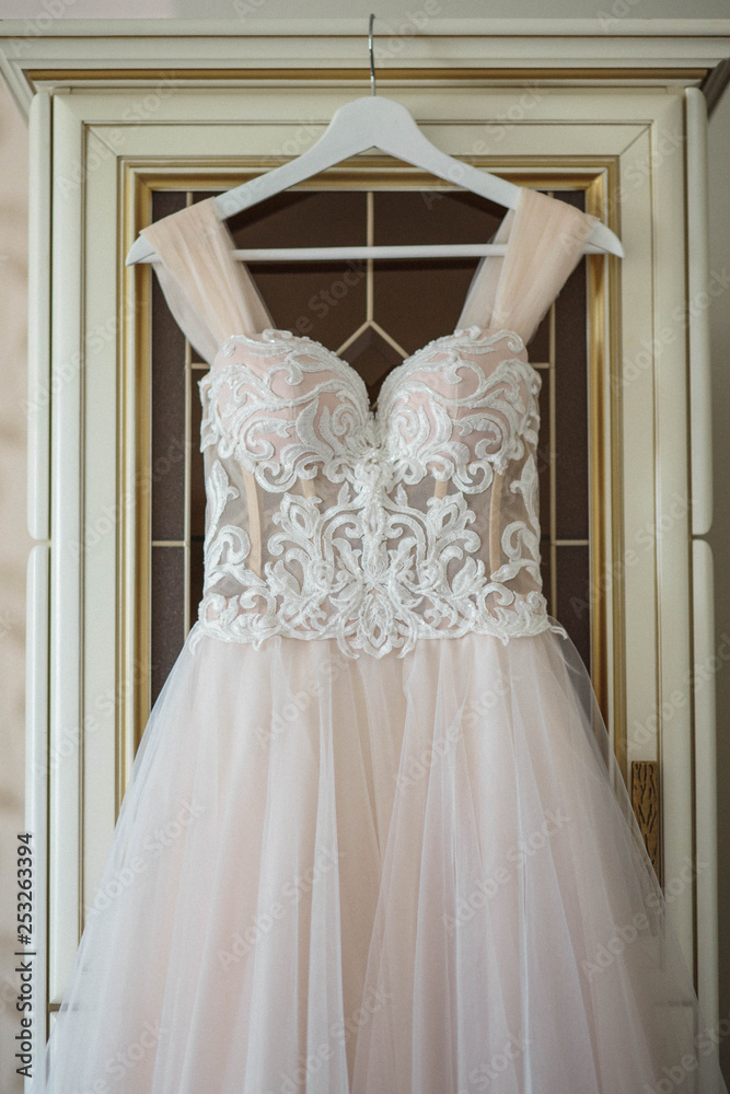 wedding dress on hanger on a wall. Beautiful gown wedding dress on hanger on a wall. Beautiful gown