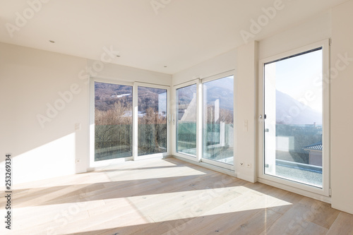 Empty room with white walls and windows overlooking the mountains