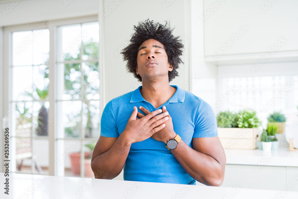 African American man at home smiling with hands on chest with closed eyes and grateful gesture on face. Health concept. African American man at home smiling with hands on chest with closed eyes and grateful gesture on face. Health concept.