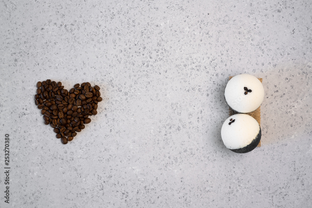 Coffee essential oil in a glass bottle, coffee beans in shape of heart on grey background Coffee essential oil in a glass bottle, coffee beans in shape of heart on grey background