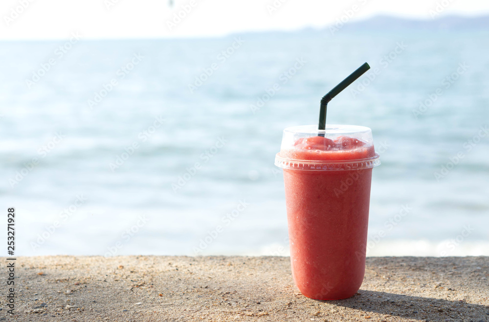 Closeup glass of strawberry smoothie with lignt in the morning and sea water background, Holiday and relax time Closeup glass of strawberry smoothie with lignt in the morning and sea water background, Holiday and relax time