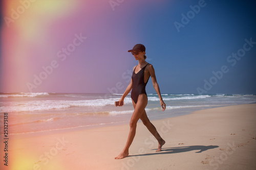 Beautiful girl walk on beach on ocean with phone