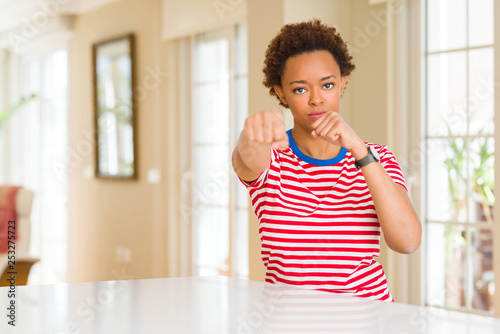 Young beautiful african american woman at home Punching fist to fight  aggressive and angry attack  threat and violence