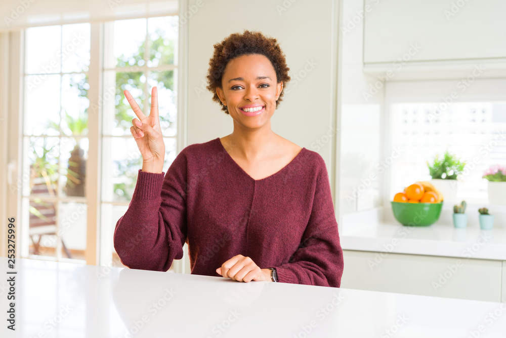 Young beautiful african american woman at home smiling with happy face winking at the camera doing victory sign. Number two. Young beautiful african american woman at home smiling with happy face winking at the camera doing victory sign. Number two.
