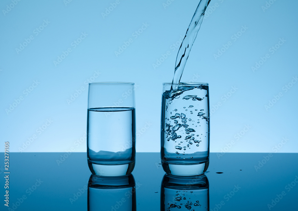 Creative splashing water in the glass on blue background. Creative splashing water in the glass on blue background.
