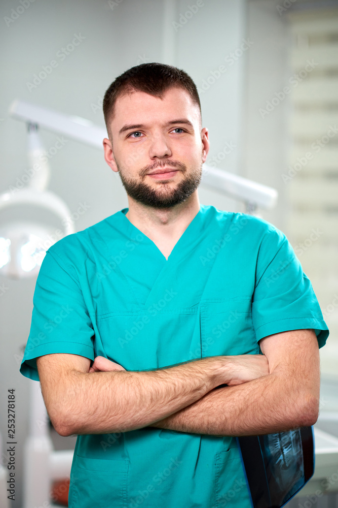 Caucasian male dentist holding xray in hands and smiling Caucasian male dentist holding xray in hands and smiling