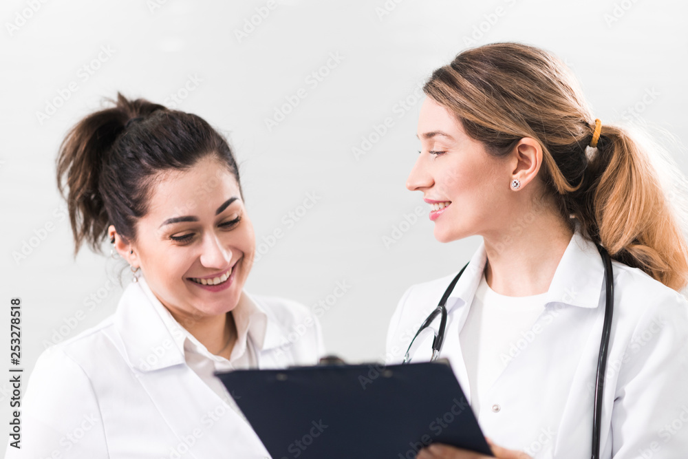 Two female assistants dressed in white coats talking to each other in the dentistry center Two female assistants dressed in white coats talking to each other in the dentistry center