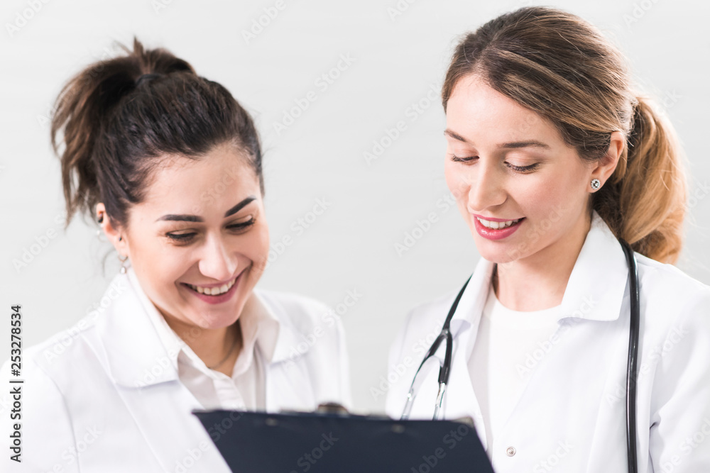 Two female assistants dressed in white coats talking to each other in the dentistry center Two female assistants dressed in white coats talking to each other in the dentistry center