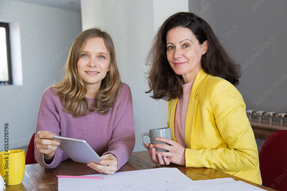 Smiling female architects drinking tea and using tablet Smiling female architects drinking tea and using tablet